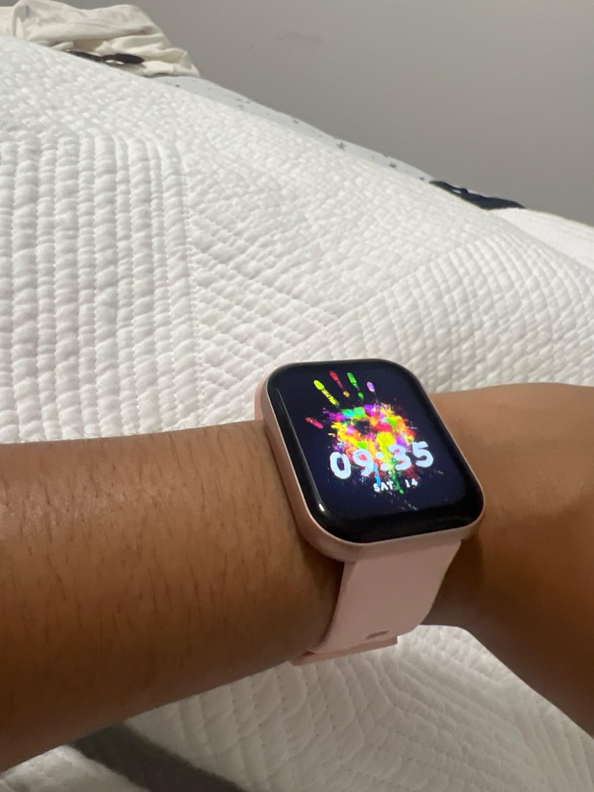 Review photo of a smartwatch with a pink band on a wrist
